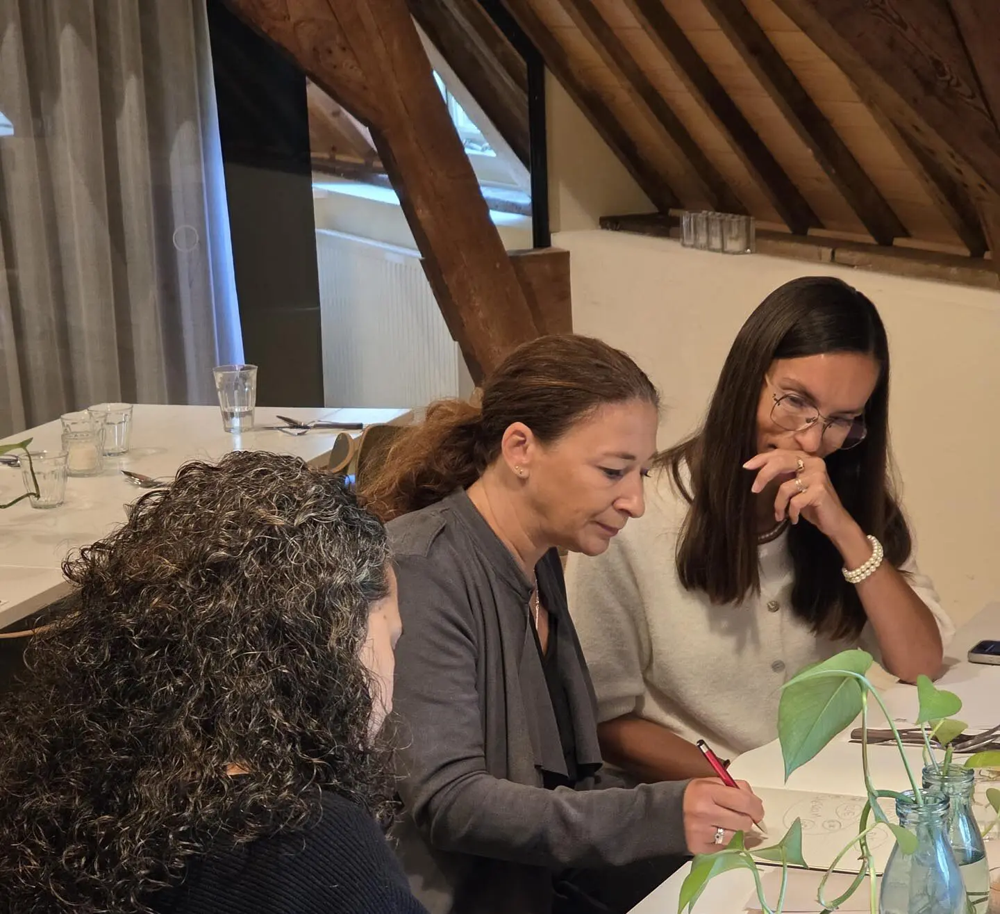 Drie associates aan tafel, Raquel zit in het midden