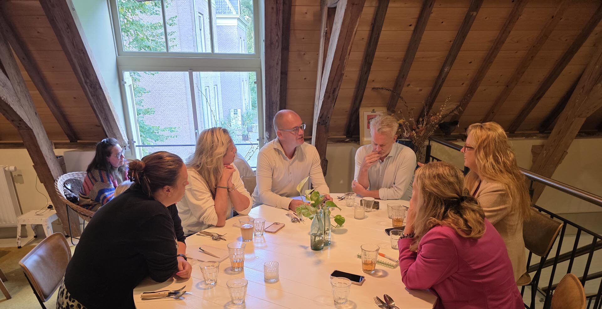 Zes associates zitten rond een ovale tafel